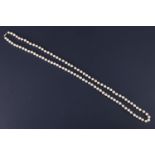 A vintage opera length string of cultured pearls, knotted with a 9 ct white metal barrel clasp