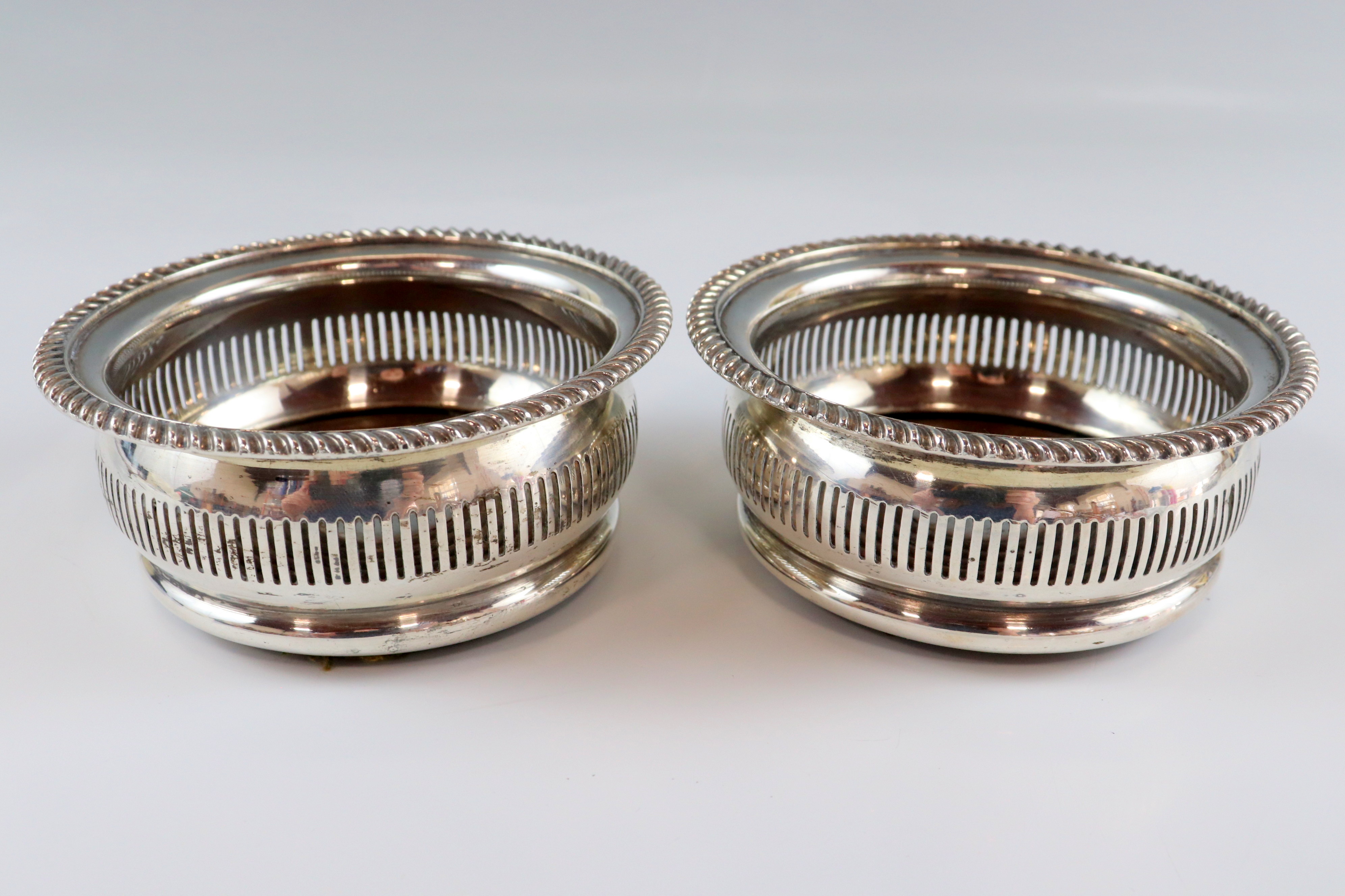 A pair of diminutive early 19th Century Sheffield plate coasters, each having ovoid sides with