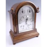 An Edwardian oak dome top mantle clock, striking on two gongs, the silvered dial having an applied