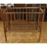 An Edwardian child's collapsible oak cot, having a sprung steel base, 62 x 122 x 120 cm