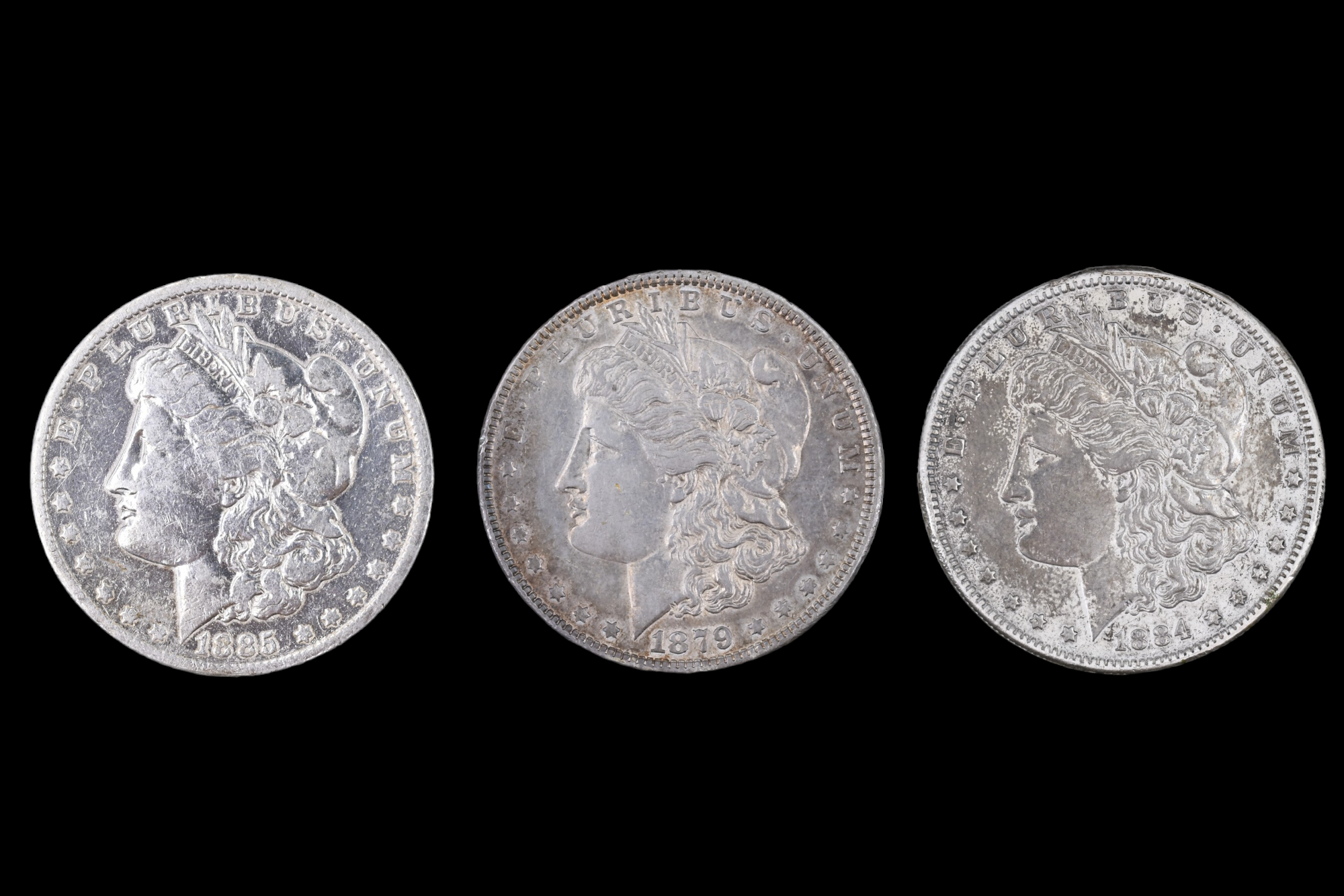 Three silver US "Morgan Dollar" coins, comprising an 1884 San Francisco, an 1885 New Orleans, and an - Image 2 of 3