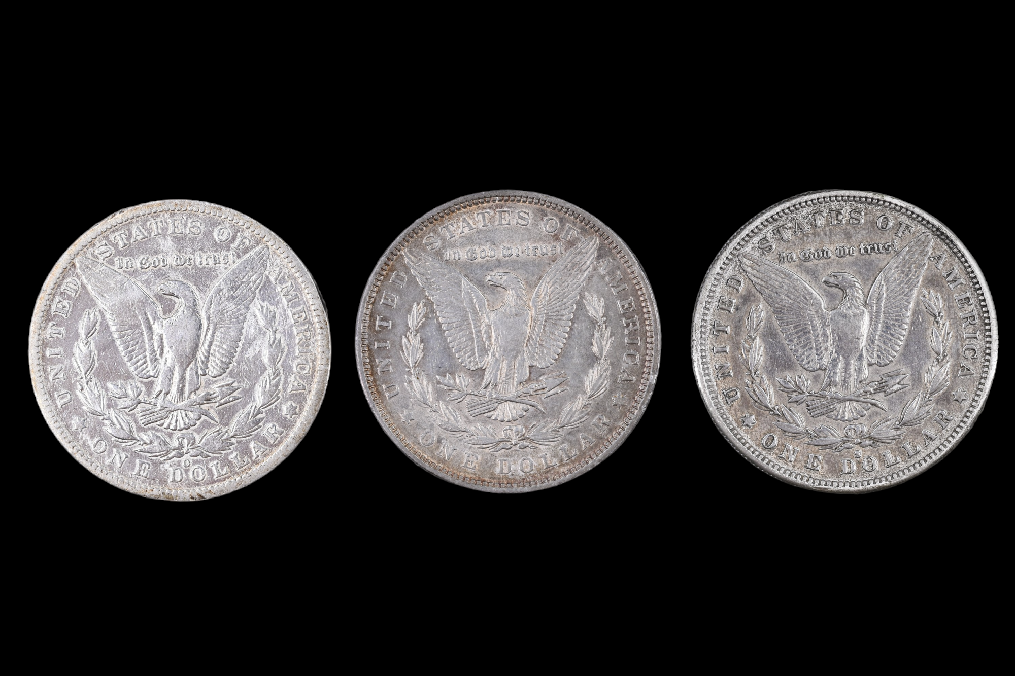 Three silver US "Morgan Dollar" coins, comprising an 1884 San Francisco, an 1885 New Orleans, and an