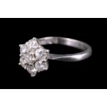 A seven stone diamond daisy ring, having a central brilliant set above a surrounding annulus of