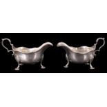 A pair of George V silver sauce boats, having gadrooned rims and raised on shell-form legs,