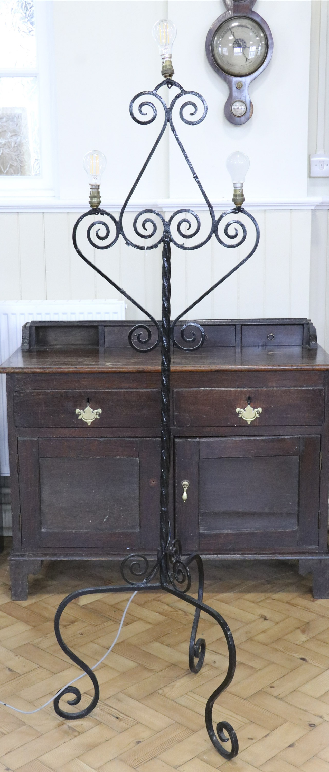 A mid-to-late 20th Century wrought iron standard lamp, comprising a tripod base and scrolled top