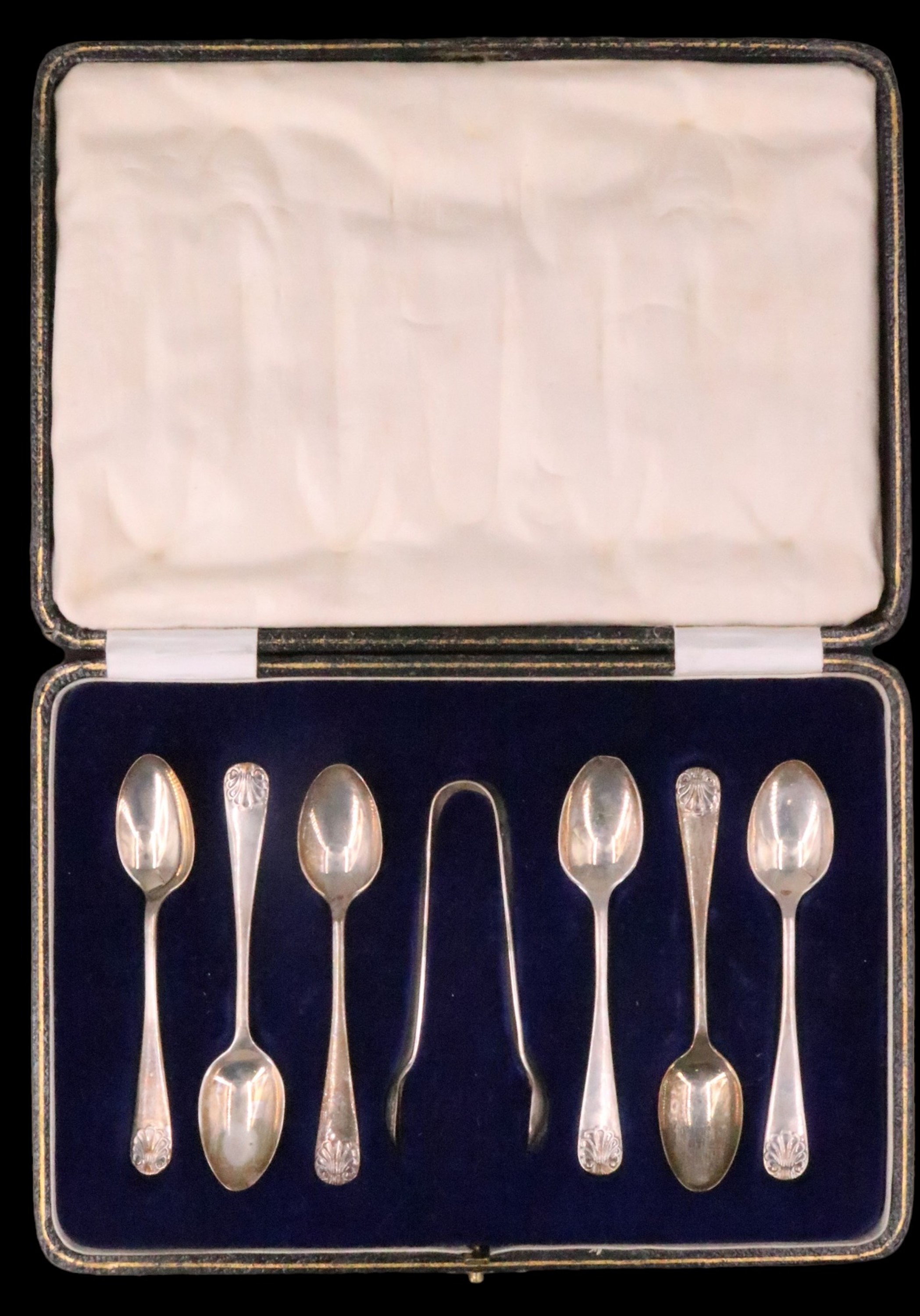 A cased set of six 1920s silver coffee spoons and sugar tongs, having anthemion decorated terminals,