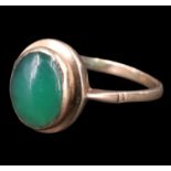 A 1970s green jade finger ring, having a 11 x 7.5 mm cabochon bezel set between tapering shoulders