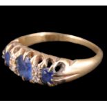 An Edwardian sapphire and diamond ring, having an oval 5 x 4 mm sapphire set between two 3 mm