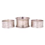 Three early 20th Century silver napkin rings, comprising a pair having floral engraving and