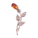 An amber and white metal floral brooch, the rose stem having three leaves and terminating in a