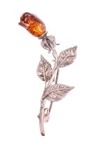 An amber and white metal floral brooch, the rose stem having three leaves and terminating in a