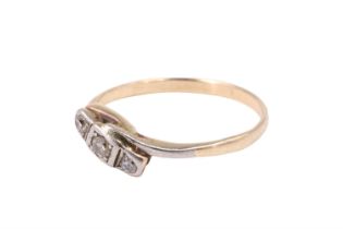 A three stone diamond crossover ring having a central 2 mm brilliant dividing two eight cuts, held