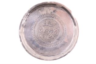 A Sudanese white metal dish, having a raised rim and a engraved calligraphic decoration,