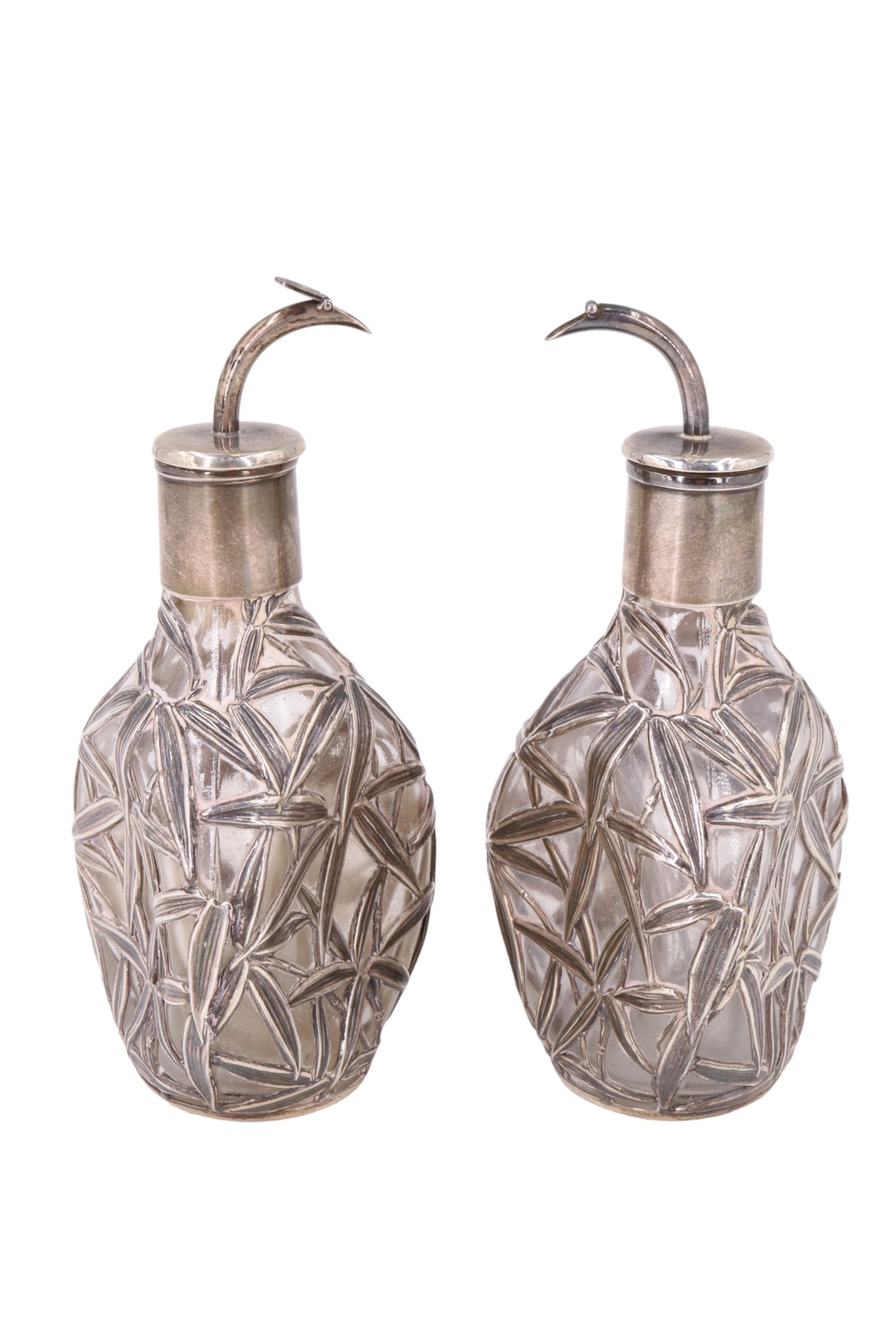 A pair of late 19th / early 20th Century white-metal-overlaid dimpled glass cologne bottles,