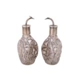 A pair of late 19th / early 20th Century white-metal-overlaid dimpled glass cologne bottles,