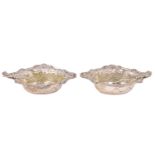 A cased pair of Edwardian silver salt cellars, having embossed decoration, associated spoons,