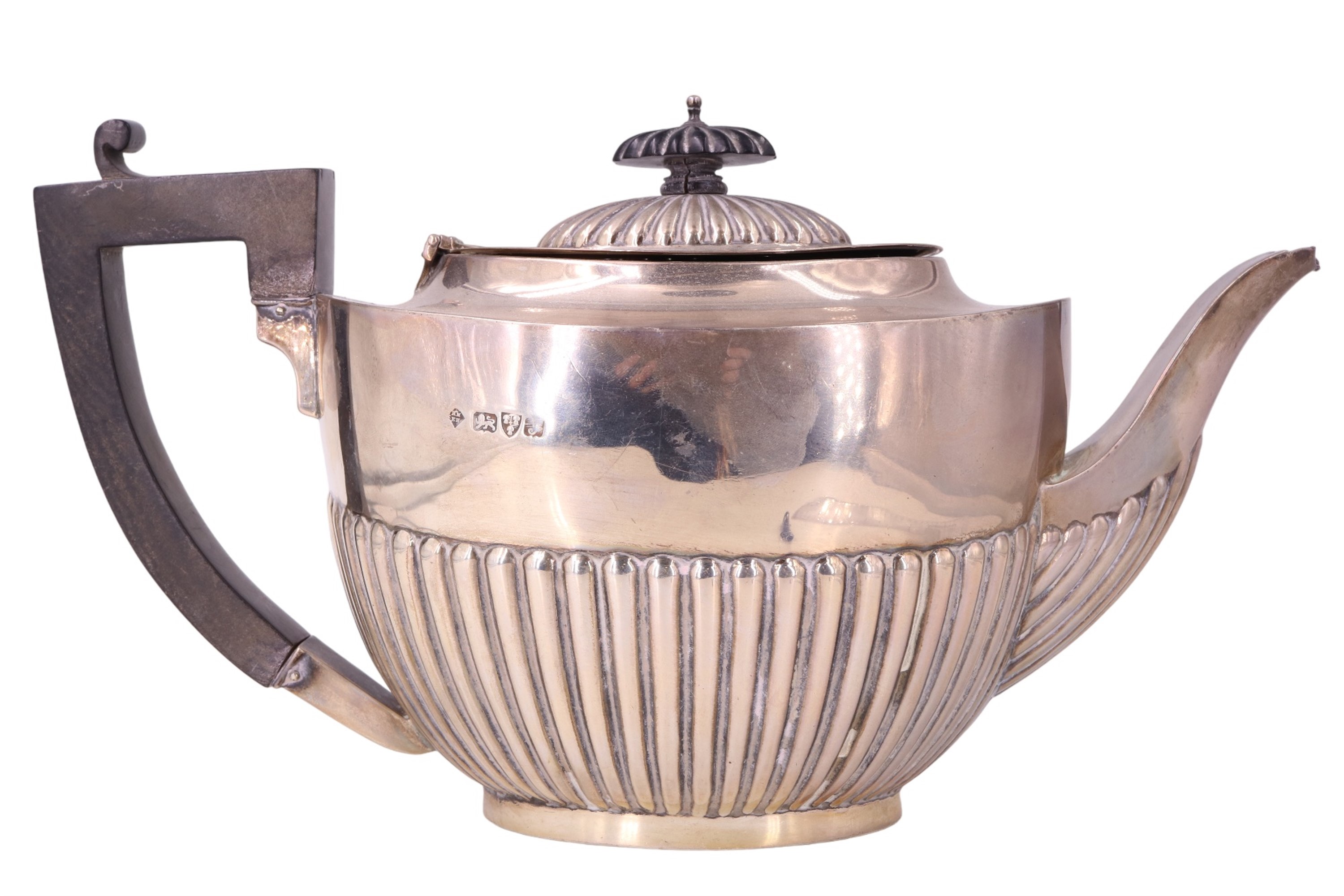 An Edwardian silver teapot, of Georgian gardrooned form, bearing moulded ribbed decoration,