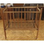 An Edwardian child's collapsible oak cot, having a sprung steel base, 62 x 122 x 120 cm