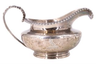 A late Georgian silver milk jug, of compressed helmet form, having a ribbed everted rim, foliate