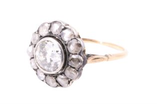 A vintage diamond cluster ring, having an 0.8 ct brilliant bezel set and surrounded by 12 old cut