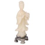 A Japanese carved soapstone figurine of a lady holding a flower standing on a contrasting carved