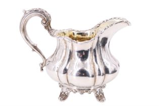 A William IV silver milk jug, of lobed compressed baluster form, with a scroll handle and gilt