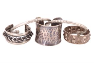 Five mid-to-late 20th Century ethnic bangles, variously having planished, punched, embossed and