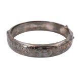 A 1960s silver bangle, decorated with engraved foliate scrolls, internal 54 x 57 mm, 26 g