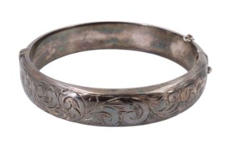 A 1960s silver bangle, decorated with engraved foliate scrolls, internal 54 x 57 mm, 26 g