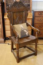 A reproduction 17th Century carved oak wainscot arm chair, 135 cm high