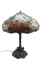 A contemporary Tiffany style patinated metal table lamp, having a cast lily pad base, a compound