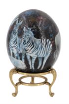 A decoupage and hand painted ostrich egg, depicting zebra and gazelle, on a brass stand, 20 cm