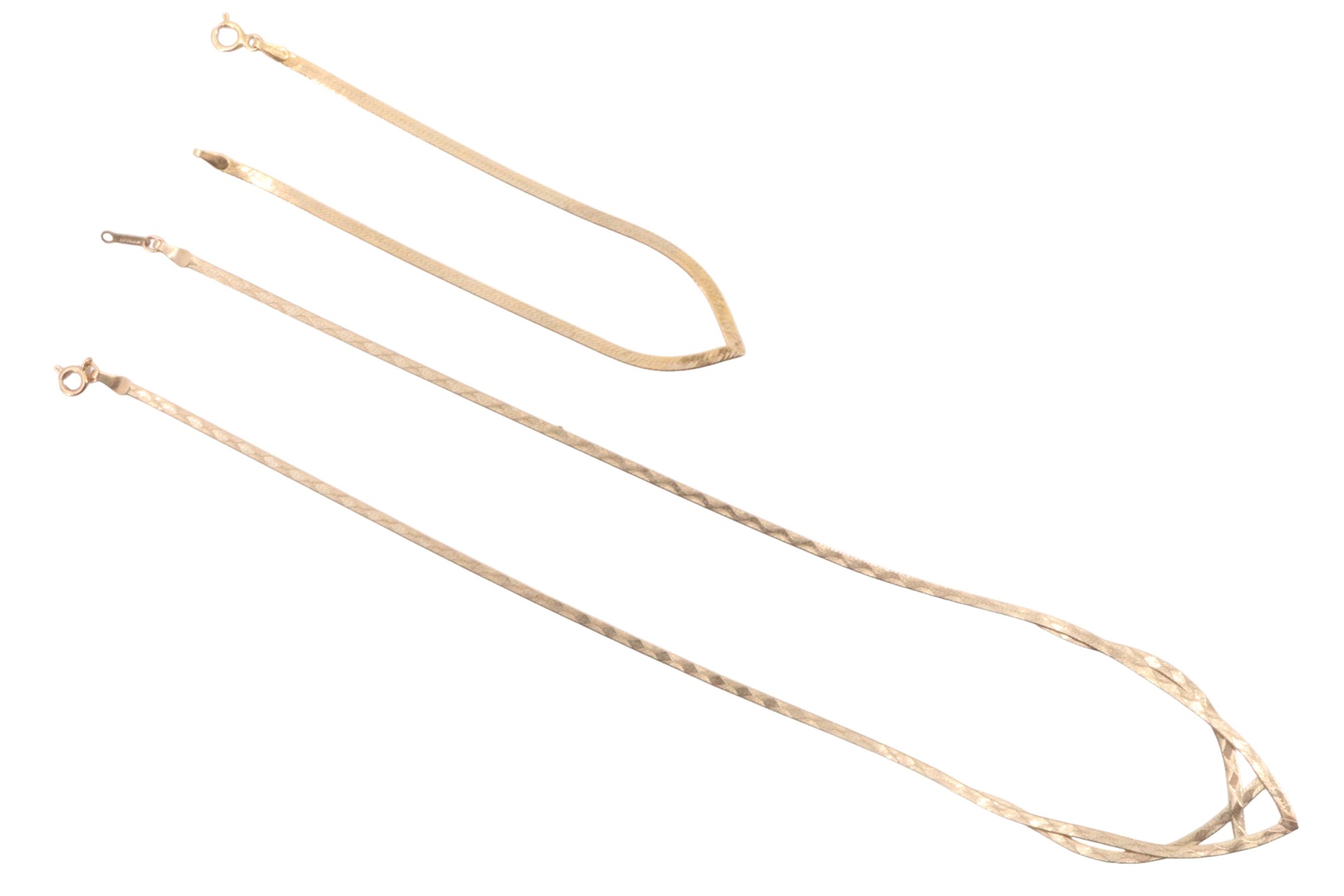 A 1980s 9 ct gold ribbon necklace, the front forming an open chevron and having engine turned