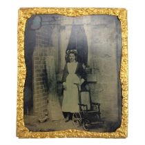 A Victorian tintype photographic portrait of a young housemaid standing in a domestic courtyard with