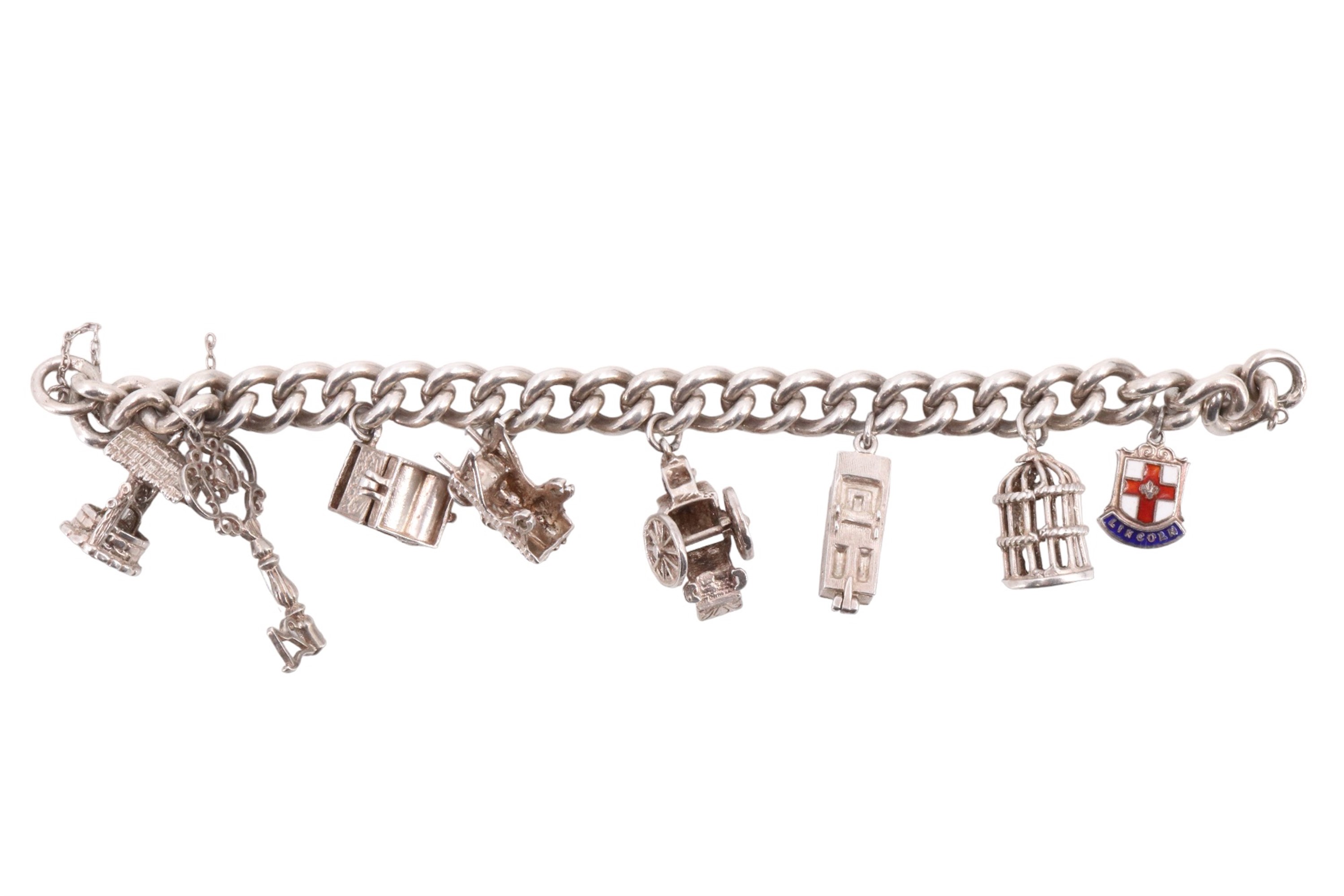 A silver charm bracelet with eight white metal and electroplate charms, including a caged bird,