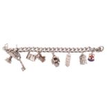 A silver charm bracelet with eight white metal and electroplate charms, including a caged bird,
