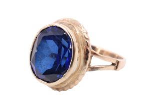 A blue sapphire finger ring, the 12 x 9 mm oval set in a bezel with a rope-twist collar to its base,