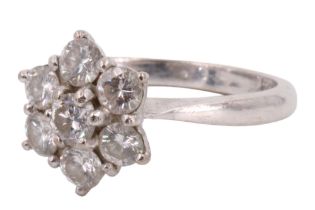 A diamond and 18 ct precious white metal ring, comprising a seven daisy-set brilliant-cut stones