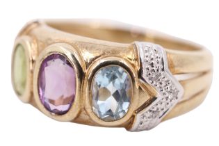 A three stone and diamond dress ring, having a 6 x 4 mm amethyst, flanked by a peridot and a blue