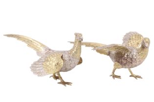 A pair of parcel gilt silver table pheasants, comprising a hen and a cock, both having wings spread,