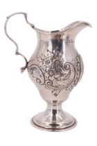 A Victorian silver footed cream jug, decorated with embossed flora and acanthus scrolls, having a