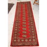 Pakistan Bokhara runner with a single row of gols on a red ground, 2.39 x 81cms together with a