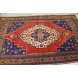 Turkish carpet with a lobed medallion and plain design with red ground, blue ground corner designs