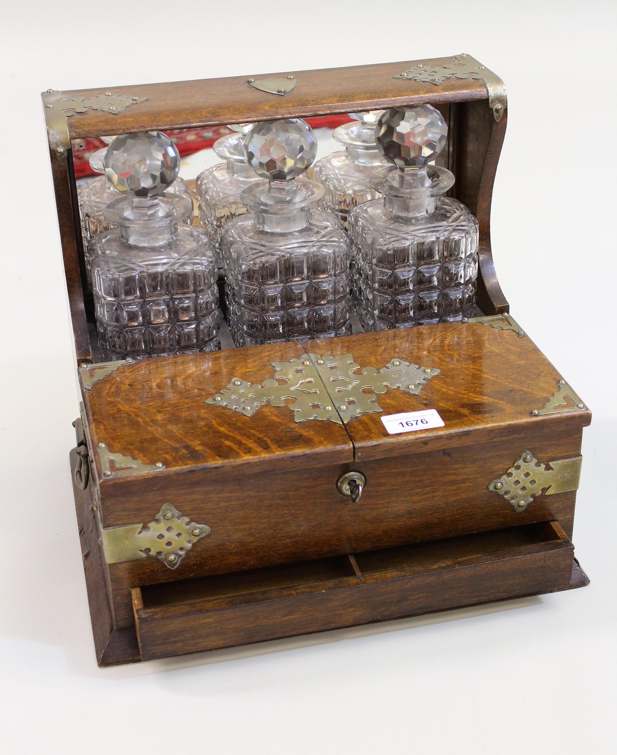 Edwardian oak and silver plate mounted three bottle tantalus, (locking mechanism requires attention)