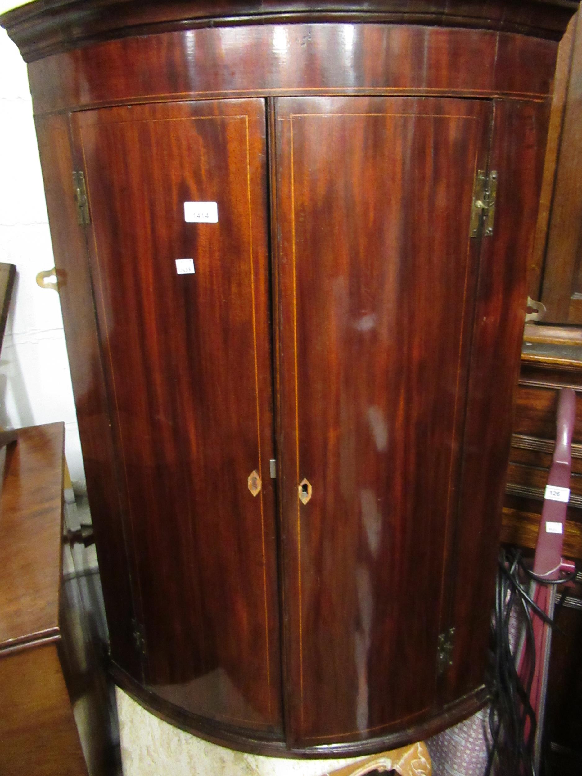 George III mahogany bow front hanging corner cabinet, the moulded cornice above a pair of line