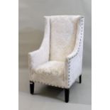 Andrew Martin, a pair of cream figured damask upholstered wing armchairs (stains to one seat)
