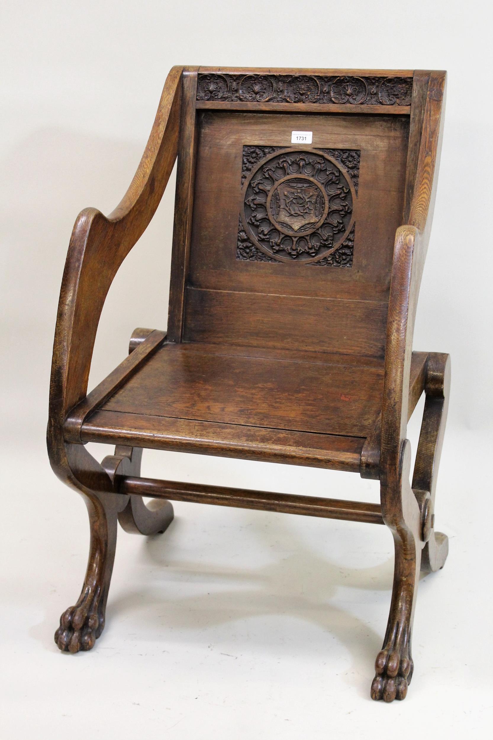 Late 19th century oak Glastonbury armchair with carved panelled back on front lions paw feet