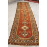 Hamadan runner with central four medallion design, and multiple borders on a red brick ground (