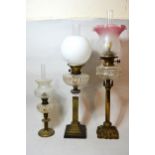 Three various brass and glass oil lamps with various shades etc. Central one has had bowl drilled