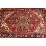 Modern Heriz carpet with a typical lobed medallion and all-over stylised floral design on a red